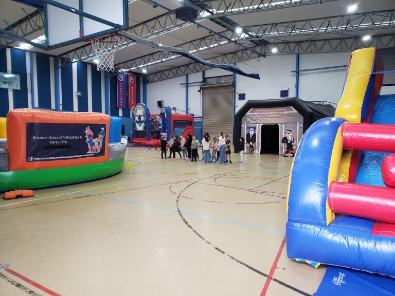 Jumping castles, inflatable nightclub and party hire setup at indoor event in Bunyip with kids enjoying activities