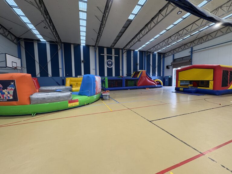 Indoor party hire setup in Longwarry featuring jumping castles and inflatable games inside a sports hall