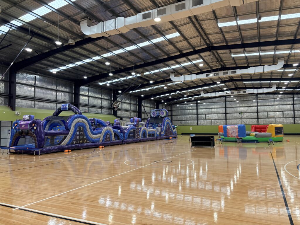 large indoor jumping castle and obstacle course setup for event hire in Warragul sports stadium