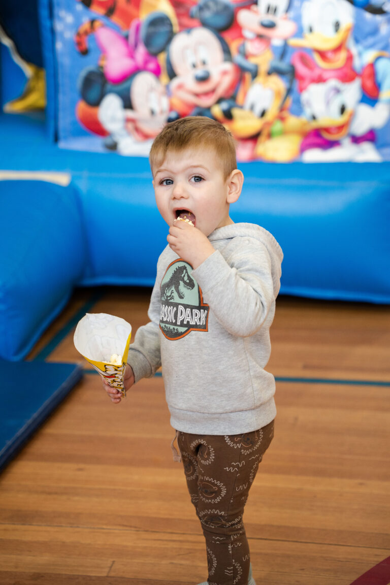 kids party hire Officer child eating popcorn jumping castle background