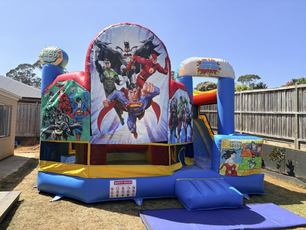 Super Hero 5-in-1 jumping castle with slide available for hire in Melbourne, featuring Batman, Superman, Flash, Green Lantern and Wonder Woman.
